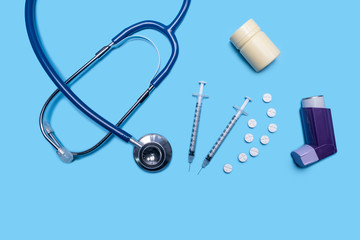 layout of health and medical care testing for checkup on patient, with inhaler, stethoscope, syringe, pills container for diagnosis and testing on ill patients wellness, on blue flat lay background