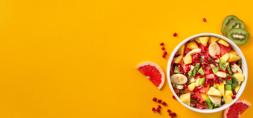 Fresh fruit salad on yellow background top view Summer food concept