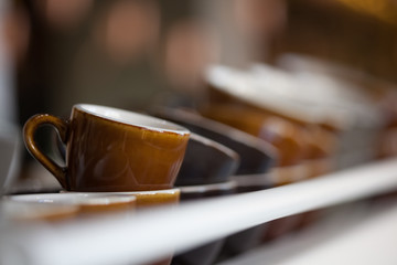 bunch of brown Loveramics ceramic coffee cups on top of espresso machine
