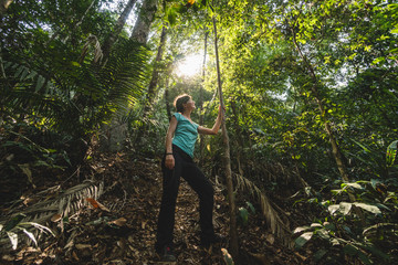 Girl looking up at the trees inside the jungle, hiking through a green forest jungle, Thailand
