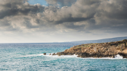 Cyprus coastline. Mediterranean rocky seashore below the storm sky.