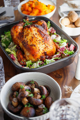 Decorated festive table with whole roasted chicken, salad, pumpkin, mushrooms, beans and walnut. The concept of family dinner or Thanksgiving celebrate.