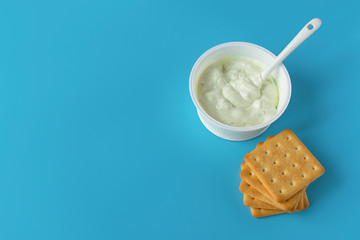 Yogurt in a glass on a blue background with salty cookies. A wholesome light diet breakfast. Dairy products..