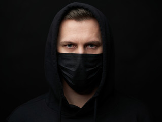 Young man wearing face mask over black background, close-up