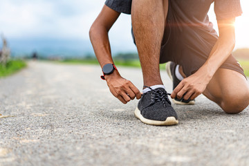 asian teenager tying shoe lace after running along the road, exercising or practicing for a...