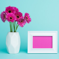 Happy Mother's Day, Women's Day, Valentine's Day or Birthday Background. Beautiful dark pink gerbera daisies in a vase and an empty picture frame greeting card.