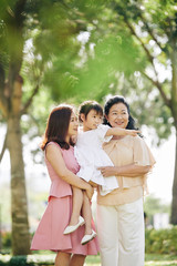 Young woman holding little daughter pointing at something interesting in city park