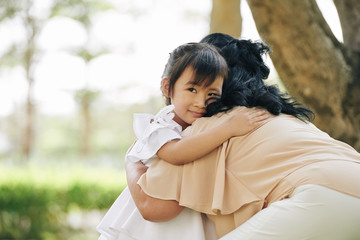 Happy little Vietnamese girl in summer hugging her grandmother