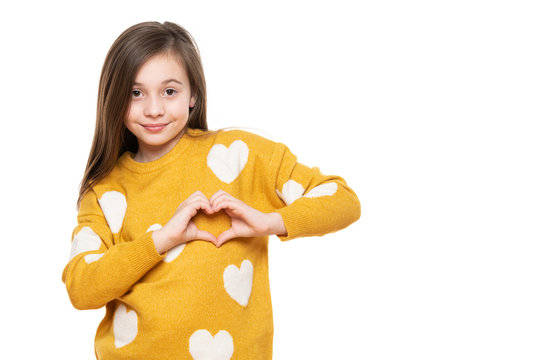 Studio portrait of a little girl on white background making a heart gesture with her hands. Fostering a child, humanitarian aid, cooperation, donation and support concept.