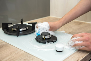 Housewife washing the gas stove with detergent in the kitchen. House cleaning
