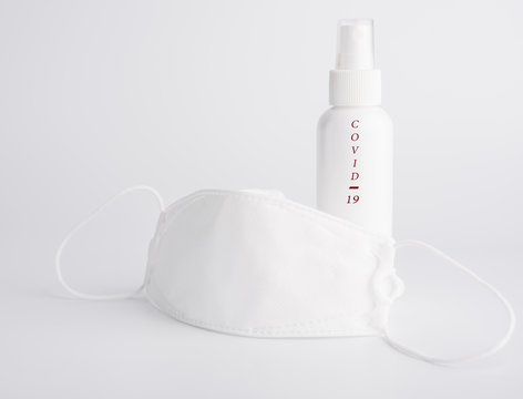 White mask and text COViD-19 for wearing germ protection  and gel alcohol or hand sanitizer spray bottle for washing hand  to protect from corona cirus set on white background