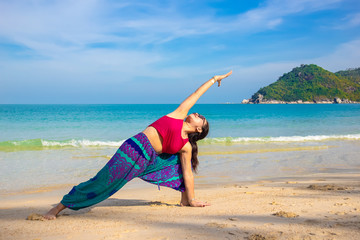 Asian Thai woman practicing yoga in Ao Thong Nai Pan Noi beach, Koh Phangan island, Thailand