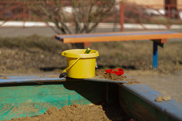 Yellow bucket and scoop on the children's sandbox on the Playground at home.