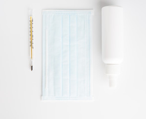 Coronavirus prevention with medical  surgical mask, hand sanitizer and thermometer on white background,top view