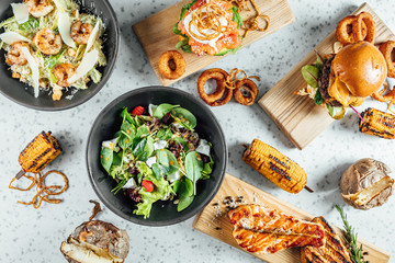 Colorful Dinner table with grilled meat, salads and burger. Restaurant food table