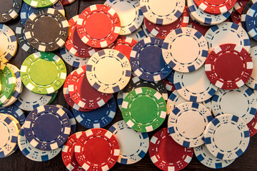 Gambling chips on dark wooden desk.