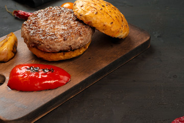 Grilled burger cutlet with a bun on wooden board, top view