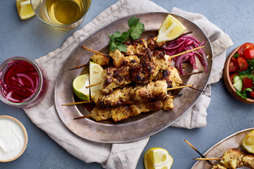 Chicken tikka kebab with marinated onion, fresh salad and yoghurt sauce. Traditional indian cuisine, delicious starter. Creative flatlay