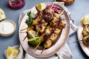 Chicken tikka kebab with marinated onion, fresh salad and yoghurt sauce. Traditional indian cuisine, delicious starter. Creative flatlay