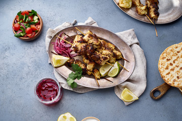 Chicken tikka kebab with marinated onion, fresh salad and yoghurt sauce. Traditional indian cuisine, delicious starter. Creative flatlay