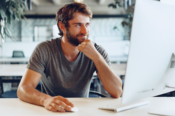 Bearded man freelancer using computer in a modern coworking place. Freelance business concept
