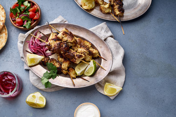 Chicken tikka kebab with marinated onion, fresh salad and yoghurt sauce. Traditional indian cuisine, delicious starter. Creative flatlay. Overhead image with text space