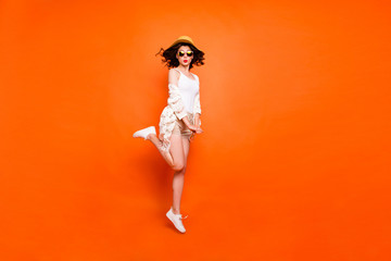 Full length photo of funny lady summer time jumping high enjoy resort views sending kisses wear sun hat specs white lace beach stylish cape shorts isolated orange background