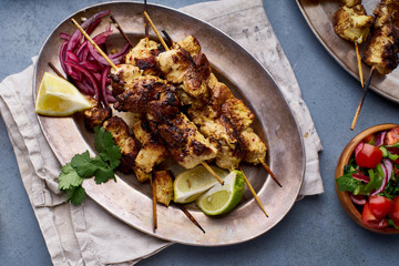 Chicken tikka kebab with marinated onion, fresh salad and yoghurt sauce. Traditional indian cuisine, delicious starter. Creative flatlay