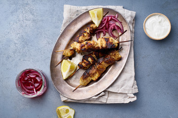Chicken tikka kebab with marinated onion, fresh salad and yoghurt sauce. Traditional indian cuisine, delicious starter. Creative flatlay