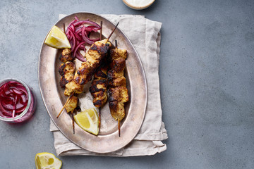 Chicken tikka kebab with marinated onion, fresh salad and yoghurt sauce. Traditional indian cuisine, delicious starter. Creative flatlay. Overhead image with text space