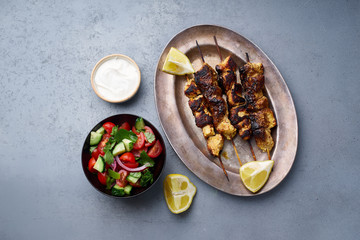 Chicken tikka kebab with marinated onion, fresh salad and yoghurt sauce. Traditional indian cuisine, delicious starter. Creative flatlay. Overhead image with text space