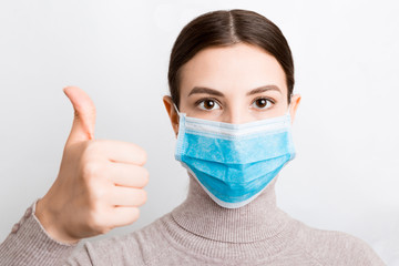 Portrait of young woman wearing medical mask at white background. Person is happy because she is finally healthy. Protect your health. Coronavirus concept