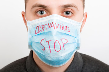 Portrait of young sick man in medical mask with stop coronavirus word at white background. Respiratory protection. Coronavirus concept