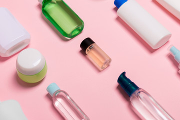 Top view of cosmetic containers, sprays, jars and bottles on pink background. Close-up view with empty space for your design