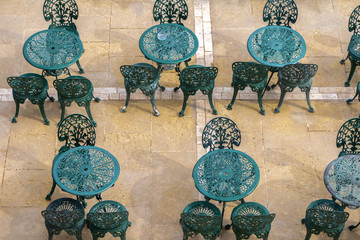 Empty terrace cafe in open air with retro style green painted metal tables and chairs from top view