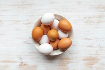 Free-range organic brown and white eggs in bowl on wooden background