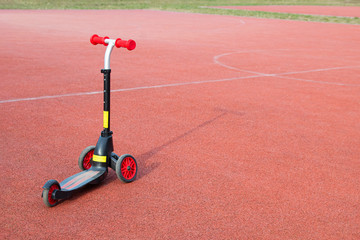 lonely scooter on a red sports field