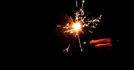 Fototapeta premium Abstract blur sparklers for celebration background,Motion by wind blurred hand holding burning Christmas sparkle on dark background.
