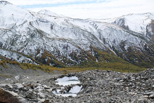 The tongue of glacier Khalde is covered with debris. Snowy peaks Dzhangi-Tau and Shkhara in background. During trekking from Khalde to Khalde glacier. Greater Caucasus, Svaneti, Georgia