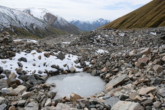 The tongue of glacier Khalde is covered with debris. Snowy peaks Dzhangi-Tau and Shkhara in background. During trekking from Khalde to Khalde glacier. Greater Caucasus, Svaneti, Georgia