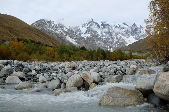 Riverbed Khaldechala with a lot of stones. Snowy peaks Dzhangi-Tau and Shkhara with Khalde Glacier in background. Greater Causasus, Svaneti, Georgia