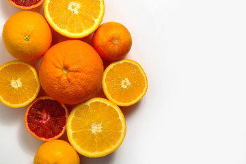 Close up image of juicy organic whole and halved assorted citrus fruits with visible core texture, isolated white background, copy space. Vitamin C loaded food concept. Top view, flat lay.