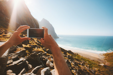 Travel blogger taking photo by smartphone influencer lifestyle summer vacations social media content creation outdoor sea Kvalvika beach landscape in Norway eco tourism