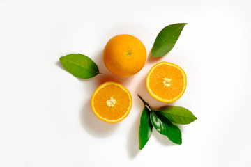Close up image of juicy organic whole and halved oranges with green leaves & visible core texture, isolated white background, copy space. Macro shot of bright citrus fruit slices. Top view, flat lay.