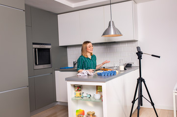 Young woman recording vlog at home in kitchen making croissants.