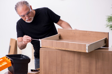 Old male carpenter working indoors
