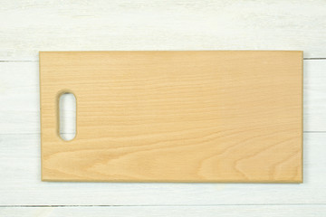 Light color cutting board lies on a white wooden background.