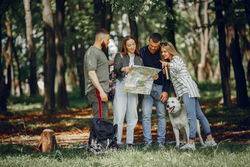 Fototapeta premium Tourists in a summer forest. Friends with a map.