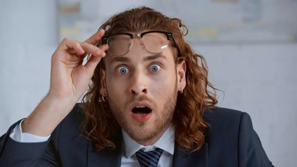 shocked and curly businessman looking at camera