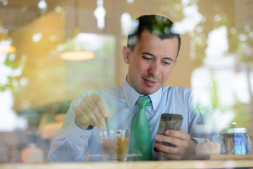 Young handsome businessman using phone at the coffee shop